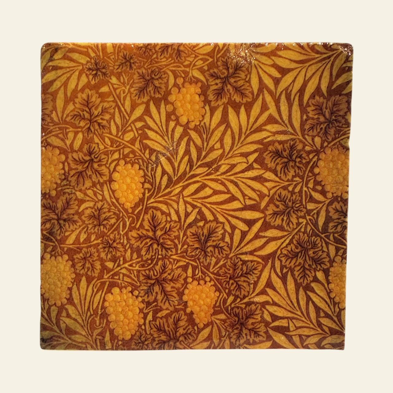 Amber colored leaf design on a stone coaster with a beige background