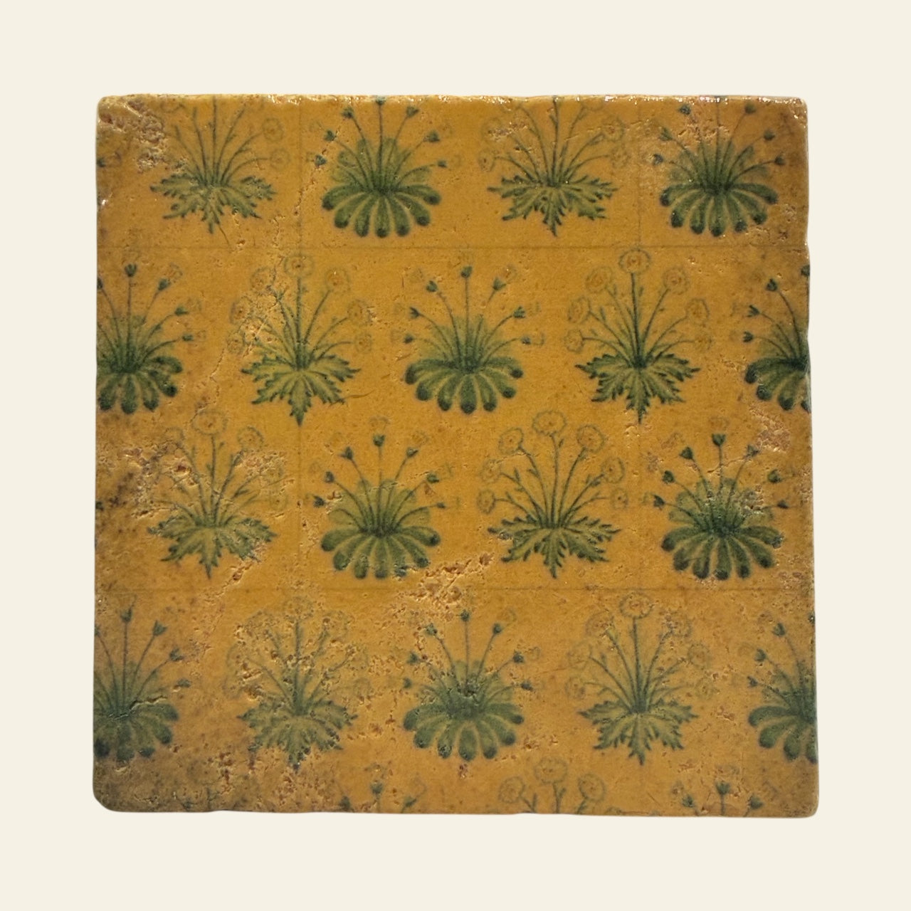 Yellow and green floral stone coaster against a beige background