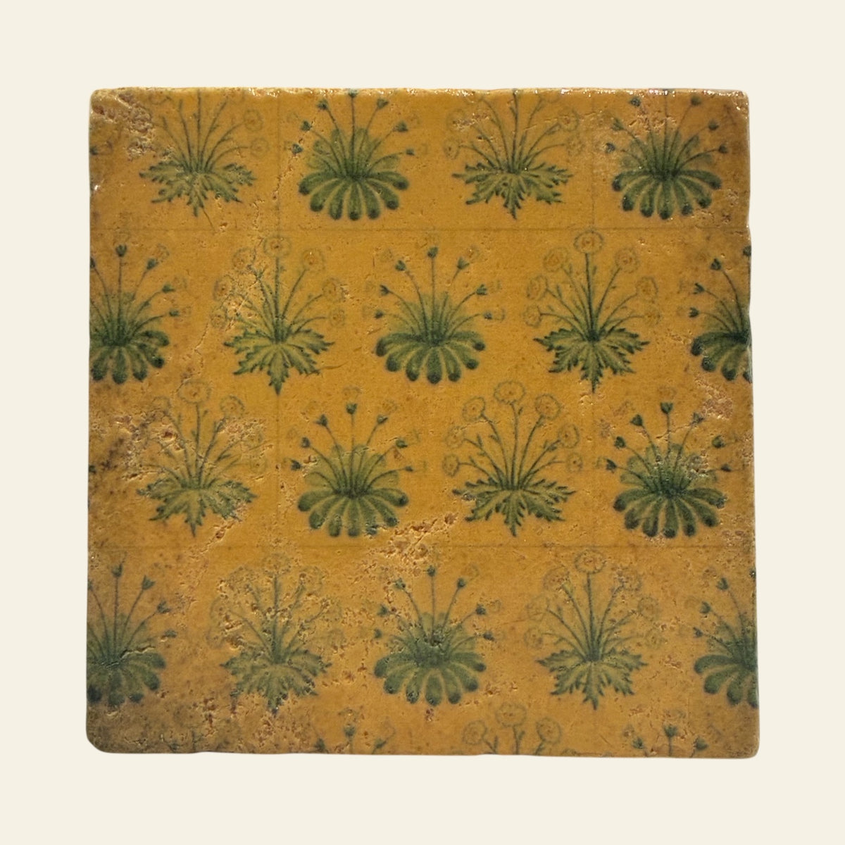 Yellow and green floral stone coaster against a beige background