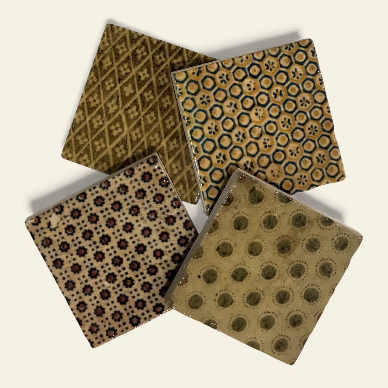 Four patterned coasters arranged on a beige background