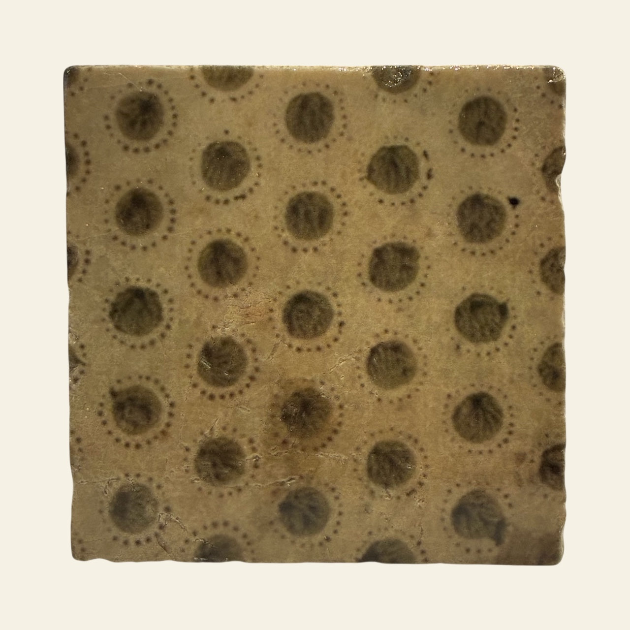 Square marble tile with circular patterns on a beige background