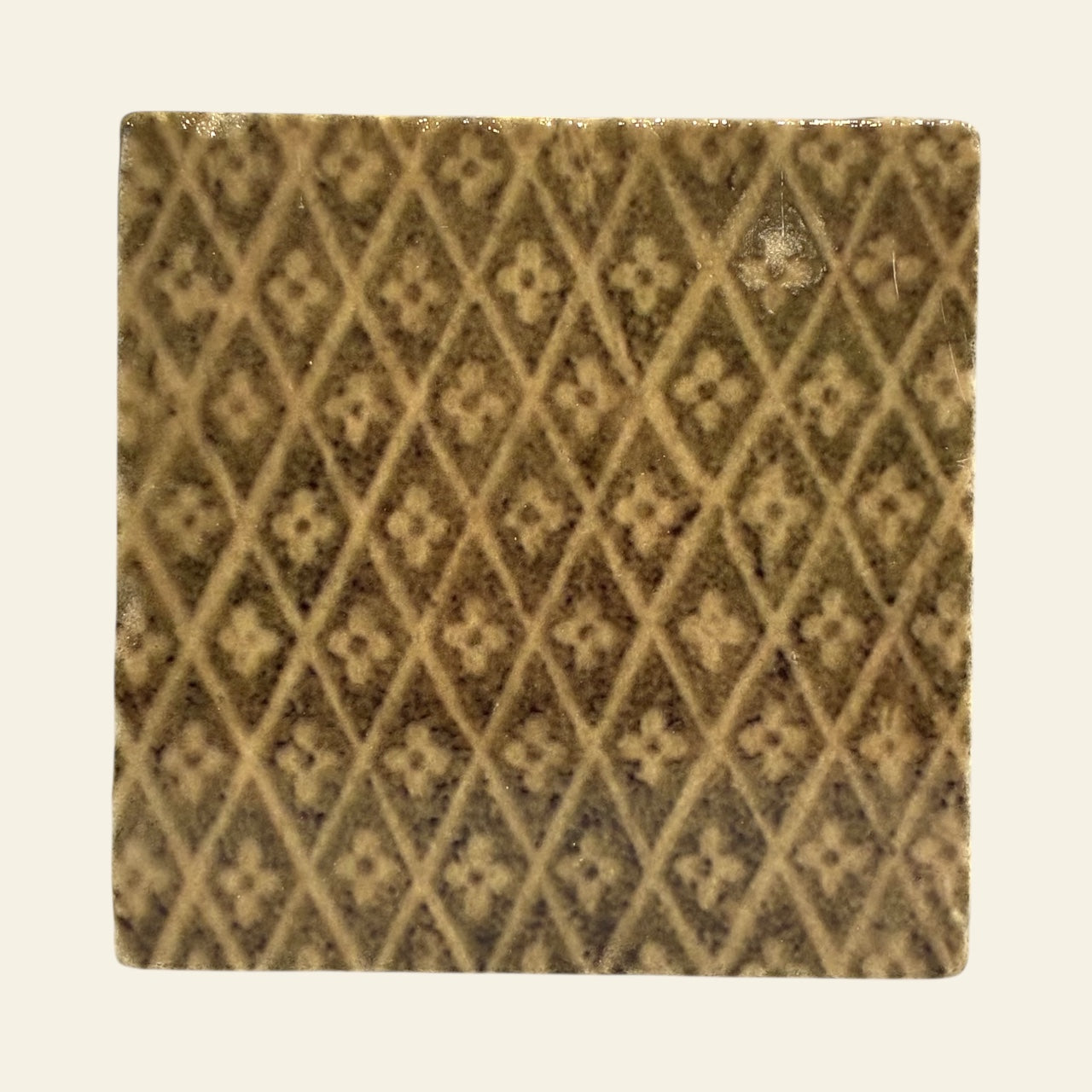 Square tile with a diamond pattern on a beige background