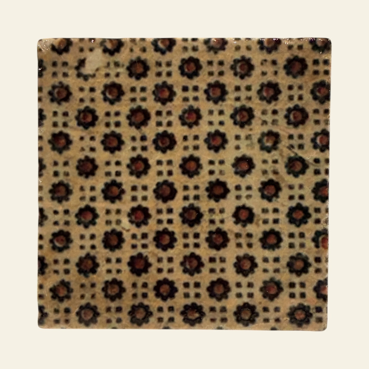 Square tile with a floral pattern on a beige background
