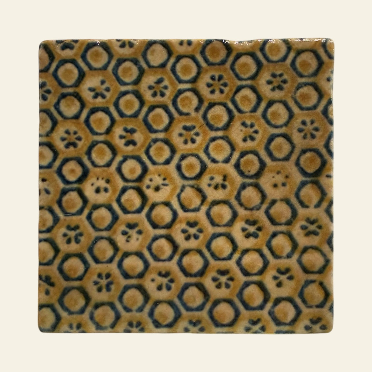 Square marble tile with hexagonal and circular pattern on a beige background