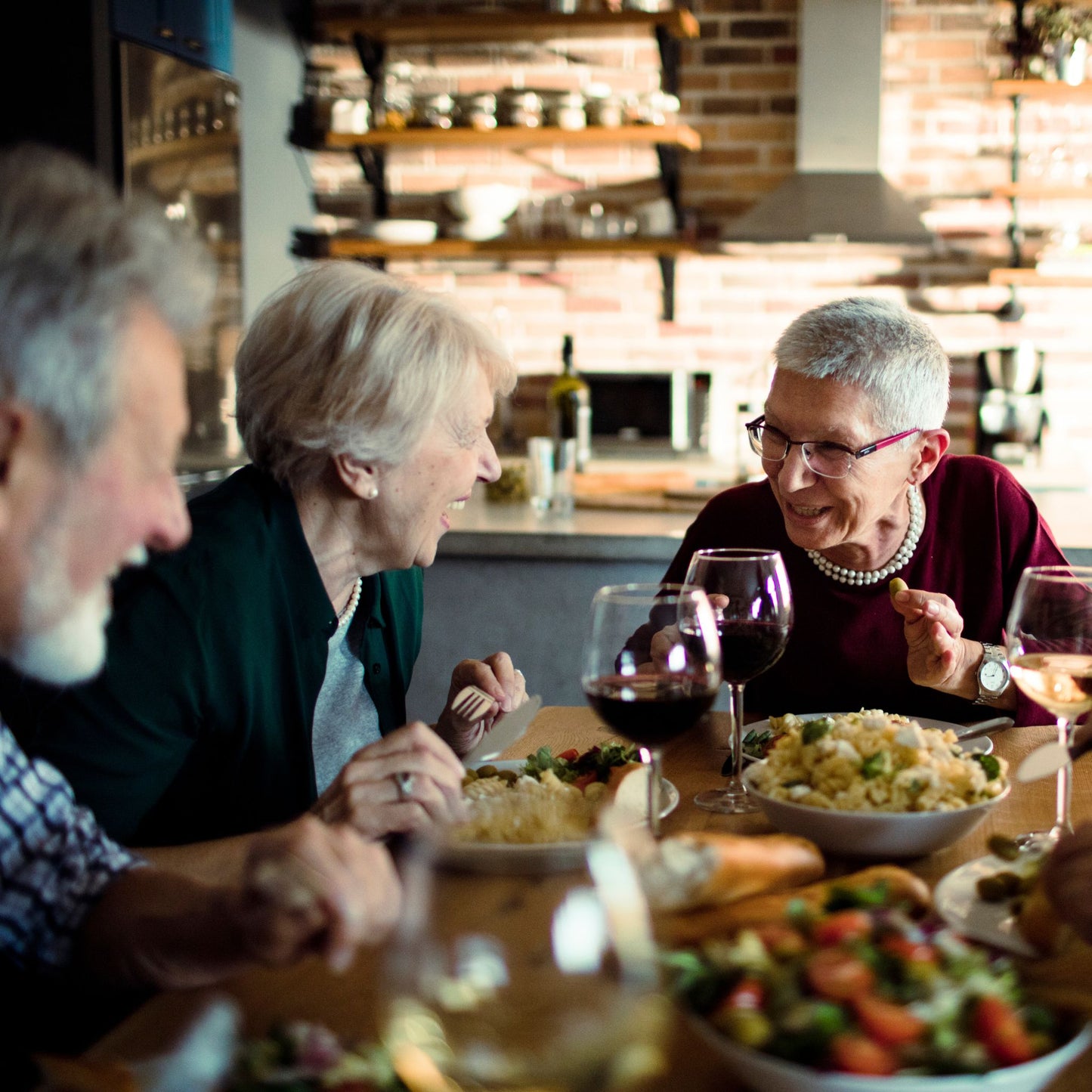 Three people enjoying a meal together at a table with wine glasses and food.