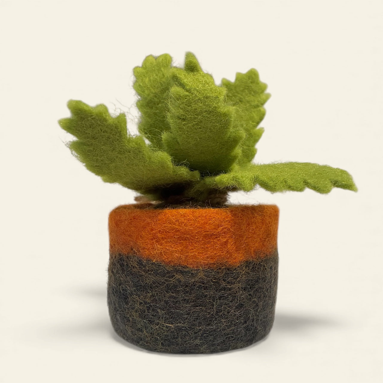 Felted plant with green leaves in an orange and grey pot on a beige background