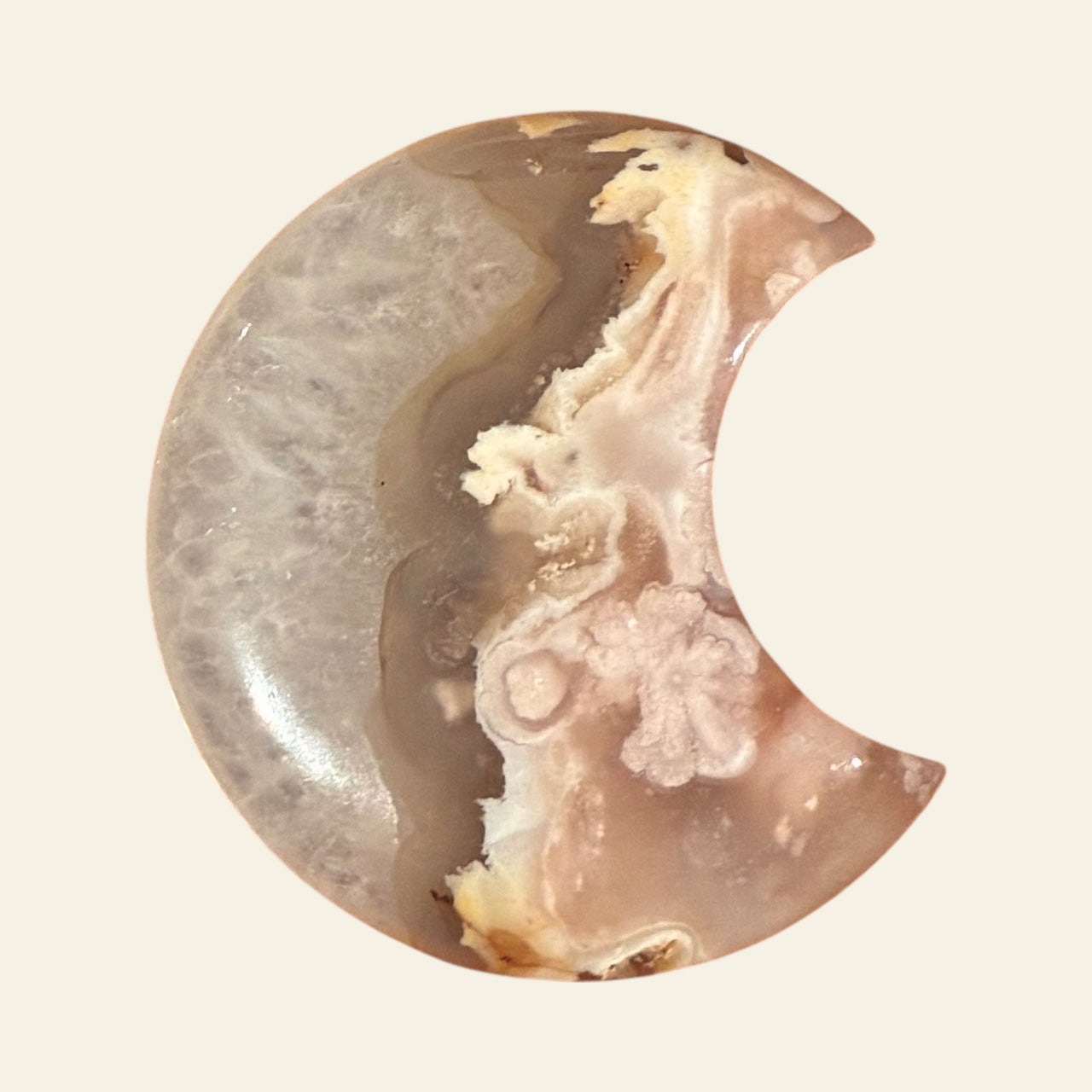 Half-moon shaped stone with a natural pattern on a beige background