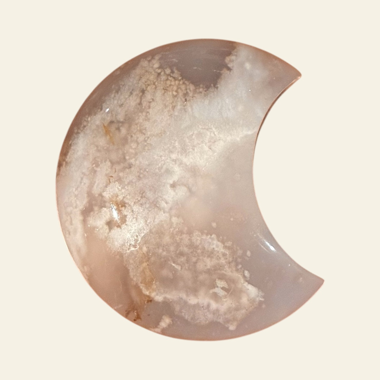 Half-moon shaped stone with a textured surface on a beige background