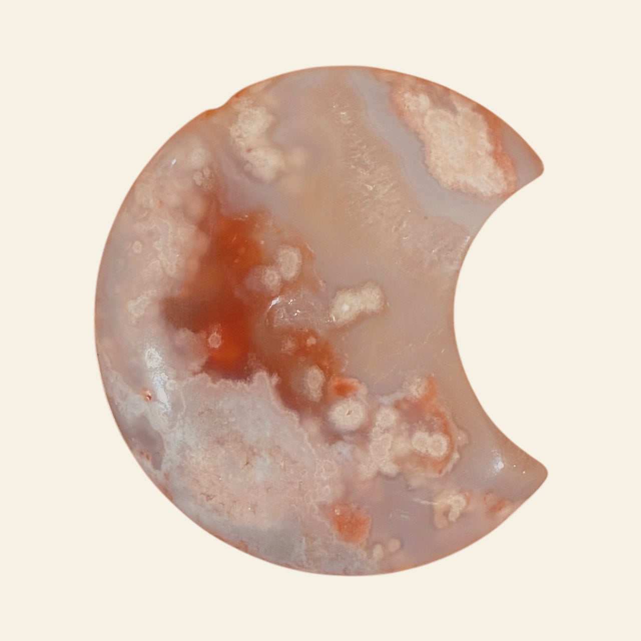 Half-cut flower agate stone with red and white patterns on a beige background