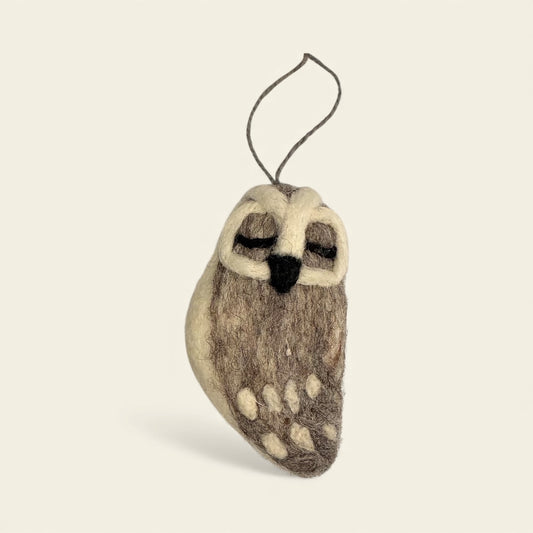 Felted owl ornament on a beige background