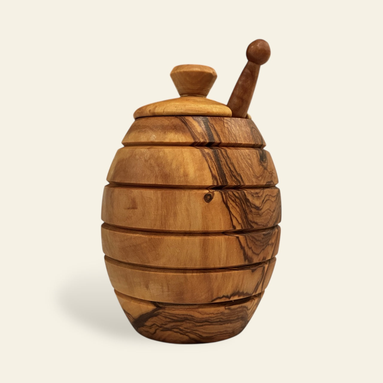 All's Well Teas and Elixirs - Light brown olive wood honey pot with a lid on a beige background.