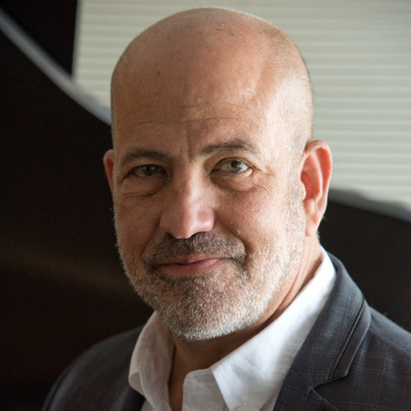 Man with a beard wearing a suit and white shirt indoors.