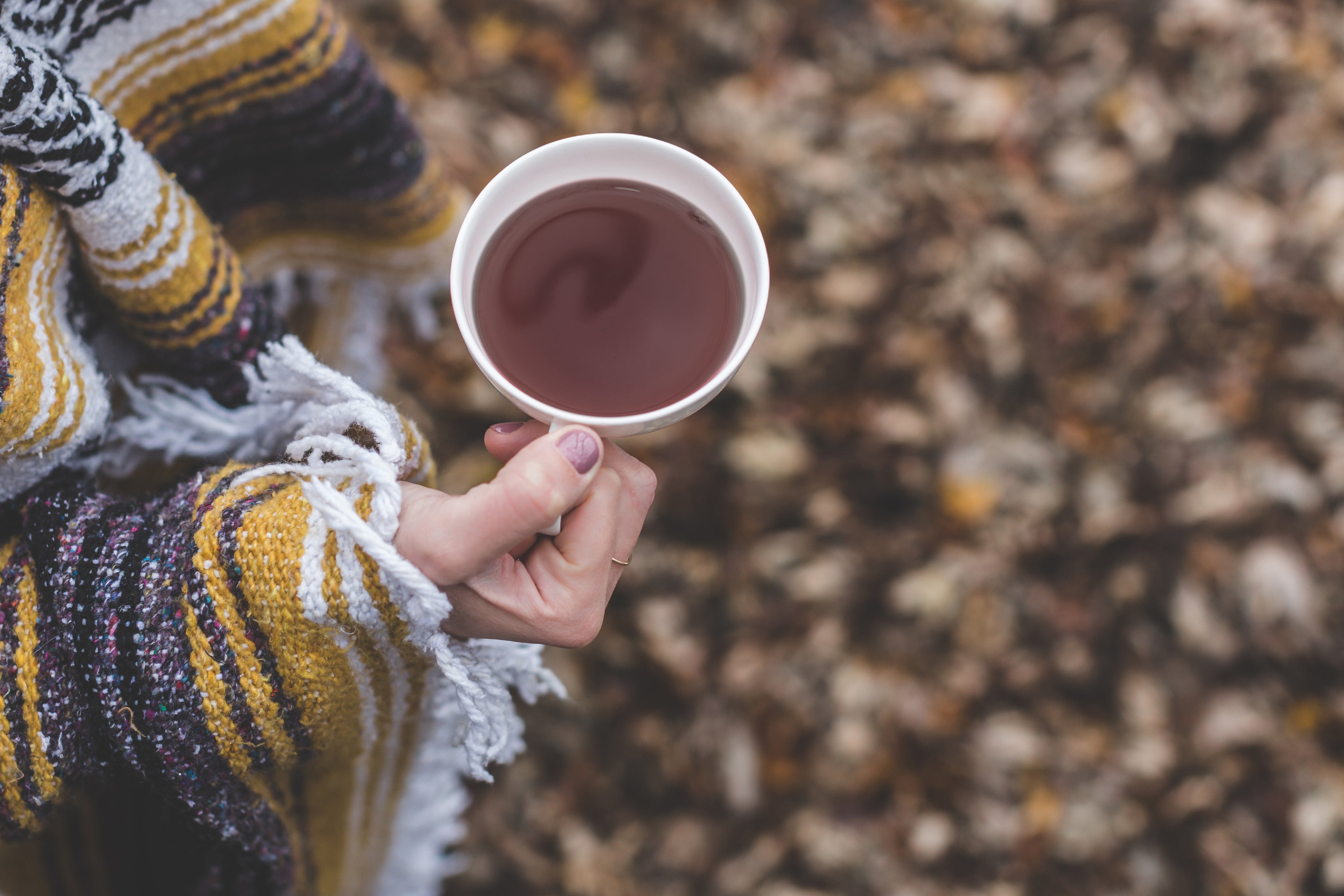 Woman wearing a cozy blanket holding a cup of tea